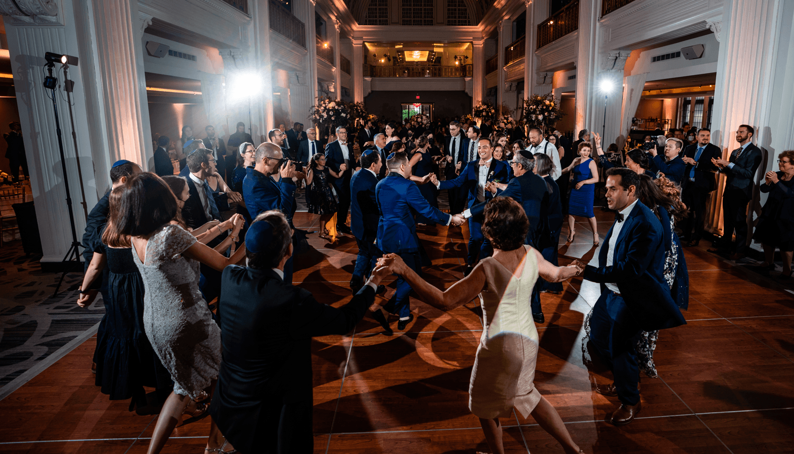 Guests dancing the Hora in a ballroom at a wedding reception