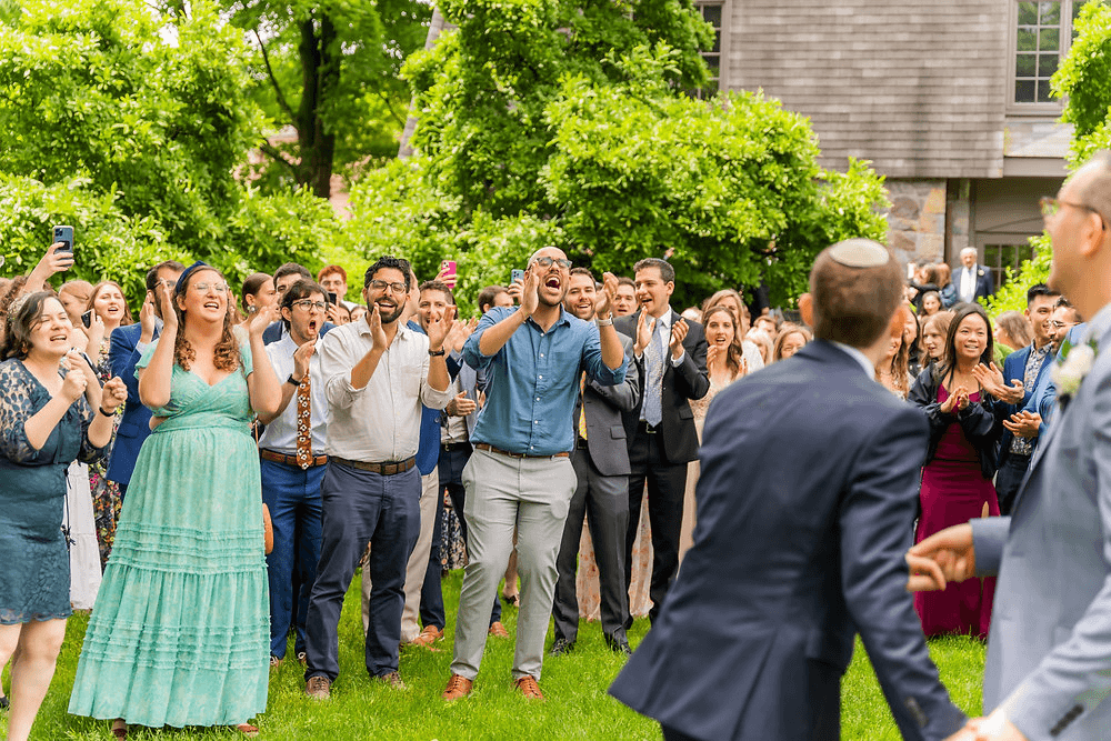 Wedding guests cheering as the couple walks by at an outdoor pre-ceremony gathering